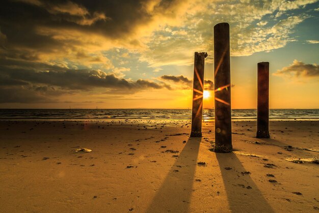 Puntos de madera en la playa contra el cielo durante la puesta de sol