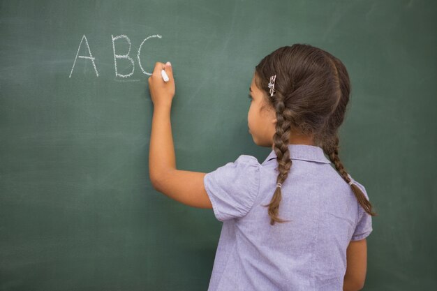 Pupila escrevendo letras em um quadro-negro