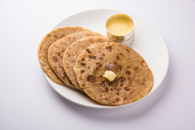 Puran Poli, también conocido como Holige, es un pan plano dulce indio que se consume principalmente durante el festival Holi. Servido en un plato con Ghee puro sobre fondo de colores o madera. Enfoque selectivo