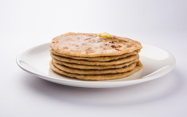 Puran Poli, también conocido como Holige, es un pan plano dulce indio que se consume principalmente durante el festival Holi. Servido en un plato con Ghee puro sobre fondo de colores o madera. Enfoque selectivo