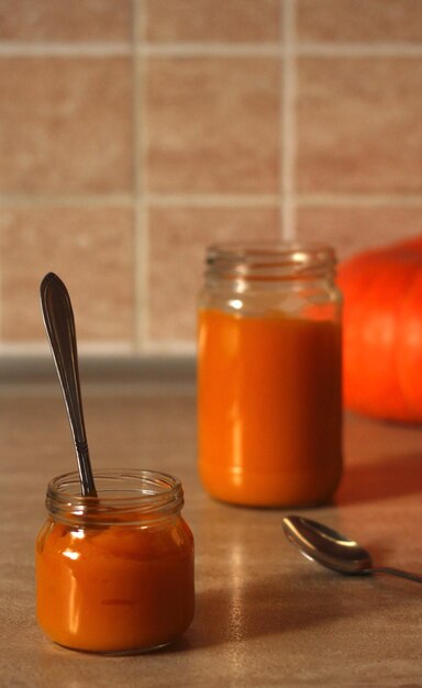 Puré de calabaza baby en un frasco de vidrio con una cuchara y calabaza fresca