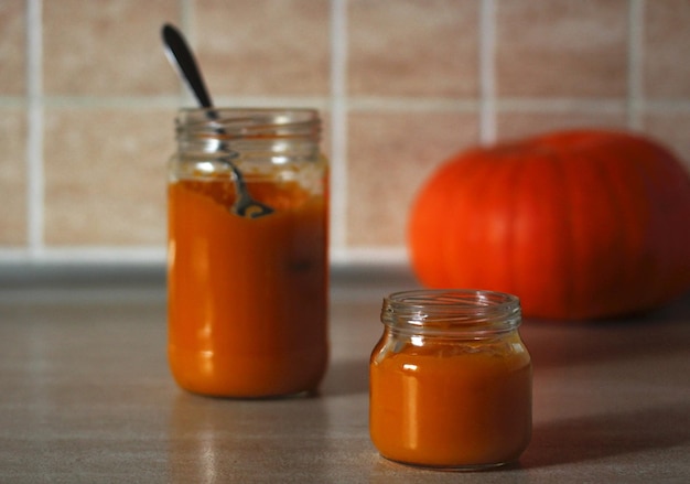 Puré de calabaza baby en un frasco de vidrio con una cuchara y calabaza fresca