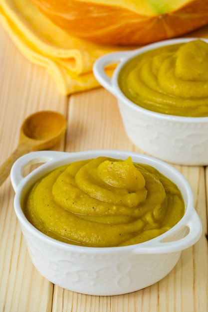 Puré de calabaza en tazones blancos sobre un fondo de madera clara.