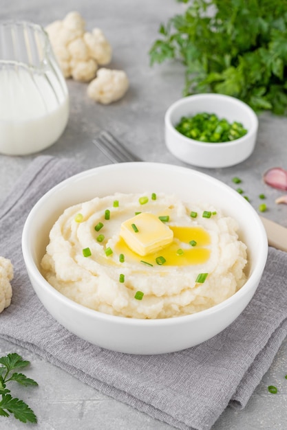 Puré de coliflor con mantequilla y cebollas verdes en un tazón blanco Comida saludable Espacio de copia