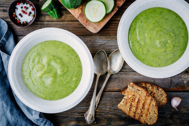 Puré de crema de verduras verdes con calabacín sobre fondo de madera