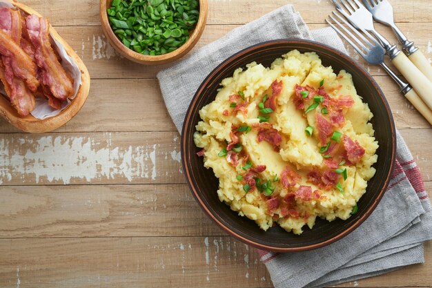 Purê de batatas Bacon purê de batatas com pimenta cebola verde e queijo cheddar em tigela sobre fundos de madeira velhos Delicioso purê de batata cremoso Vista superior