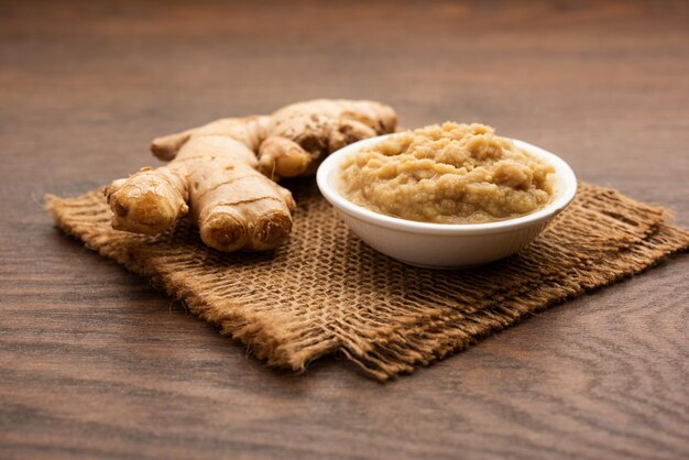 Purê de pasta de gengibre fresco ou purê em uma tigela e Adrak inteiro sobre um fundo sombrio, foco seletivo