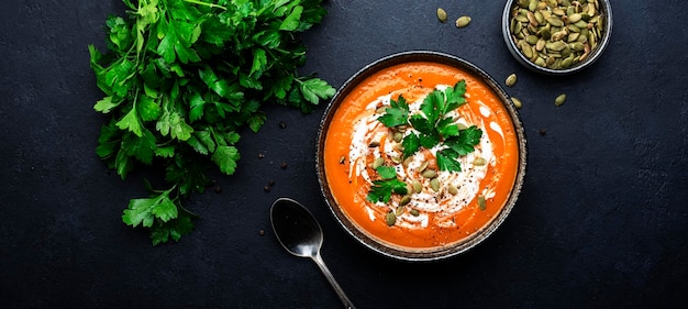 Purê de sopa de abóbora picante quente com sementes de abóbora creme de pimenta e salsa Inverno ou outono comida vegetariana vegetariana saudável Tigela de sopa no fundo preto da mesa Vista superior