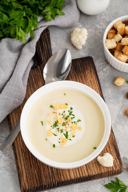 Purê de sopa de couve-flor caseira em uma tigela branca com temperos de creme de queijo e salsa fresca