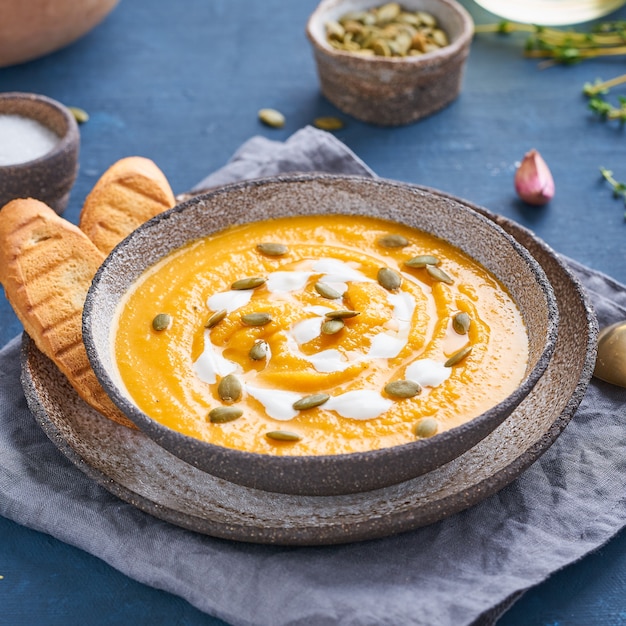 Purê de sopa de creme de pupmkin na mesa de madeira azul escura, almoço vegetariano dietético, vista lateral.