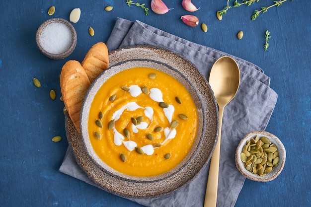 Purê de sopa de creme de pupmkin na mesa de madeira azul escura, almoço vegetariano dietético, vista superior.