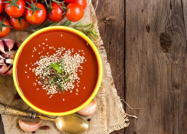 Purê de sopa de tomate fresco e legumes crus em uma mesa de madeira com espaço de cópia