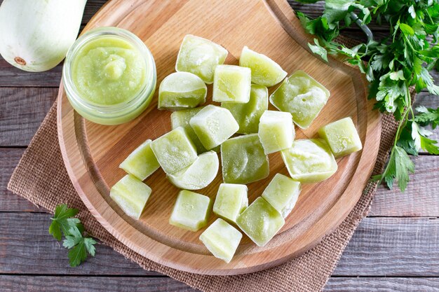 Purê de vegetais congelados na mesa de madeira. cubos de purê de abobrinha congelados. conceito de alimentos congelados.