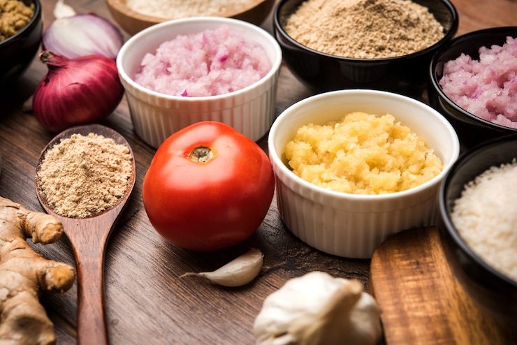 Foto puré de jengibre fresco, ajo, cebolla y tomate también conocido como pasta adrak, lahsun, pyaj y tamatar en hindi. ingredientes básicos de la comida india en un recipiente sobre fondo cambiante