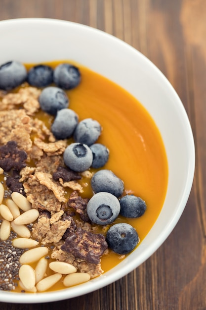 Puré de mango con granola, chia y bayas en un tazón blanco