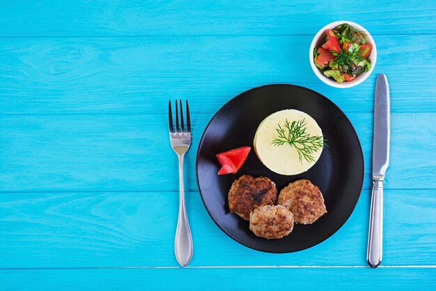 Puré de papas con chuletas sobre fondo de madera