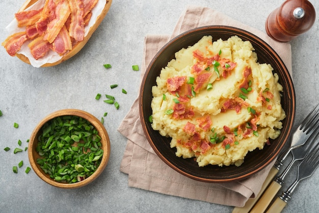 Puré de papas hervidas Puré de papas con tocino con pimiento de cebolla verde y queso cheddar en un tazón sobre fondos de madera clara Delicioso puré de papas cremoso Vista superior