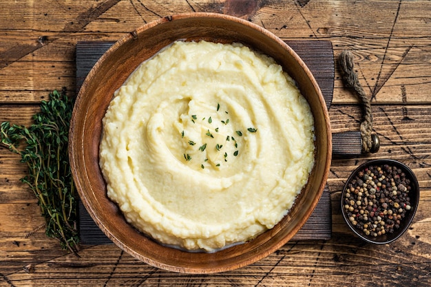 Puré de papas, puré hervido en un plato de madera. Fondo de madera. Vista superior.