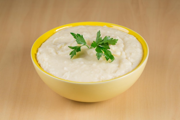 Puré de papas en tazón amarillo sobre fondo de madera