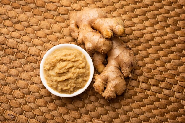 Puré de pasta de jengibre fresco o puré en un recipiente y todo Adrak sobre fondo cambiante, enfoque selectivo