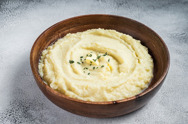 Puré de patatas hervidas, puré de patatas en una placa de madera. Fondo blanco. Vista superior.