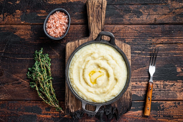 Puré de patatas en una sartén sobre la mesa rústica de madera. Fondo de madera. Vista superior.