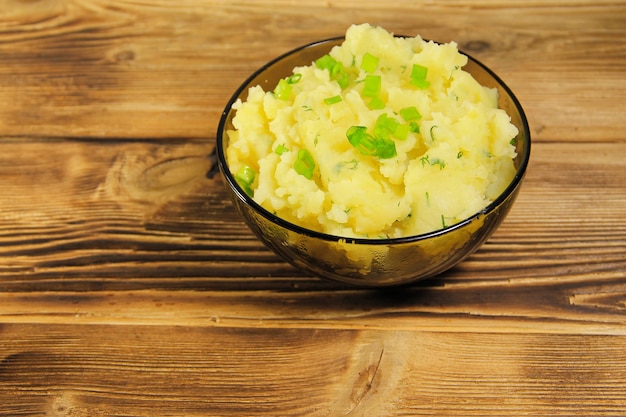 Puré de patatas en un tazón de vidrio sobre mesa de madera