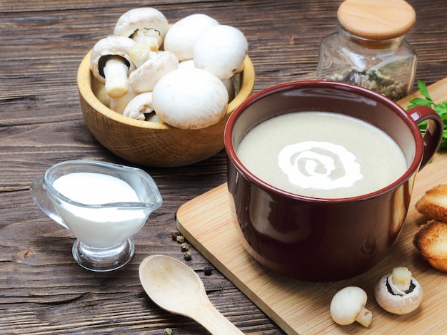 Puré de sopa de champiñones de champiñón en una taza marrón sobre una mesa de madera