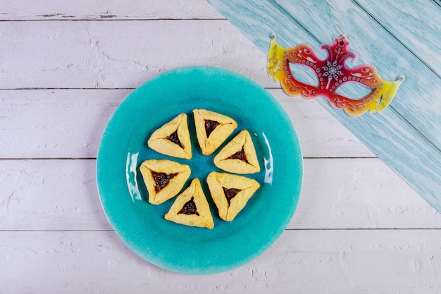 Purim con máscara y galletas triangulares.