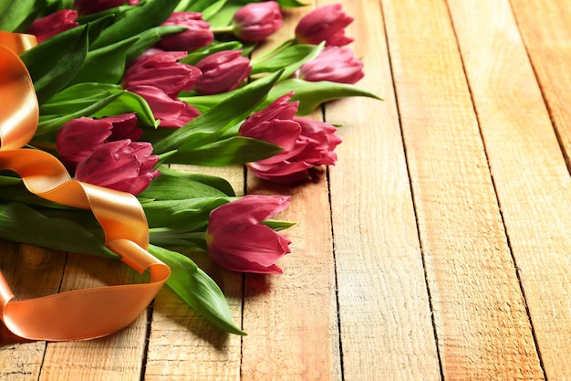 Purpurrote schöne Tulpen mit Band auf hölzernem Hintergrund