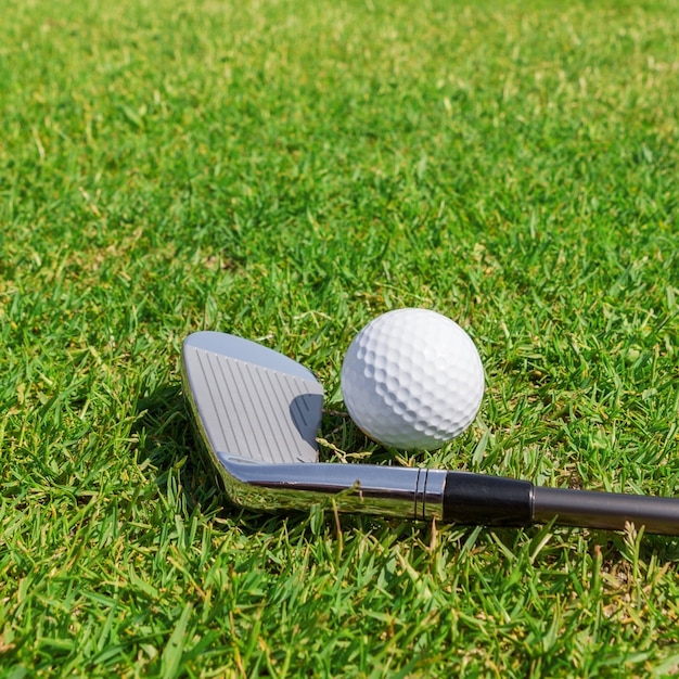 Putter und Ball auf Gras. Nahansicht.