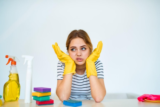 Putzfrau sitzt am Tisch mit Reinigungsmittelschwammgummihandschuhen Hausarbeitserbringungsdienste