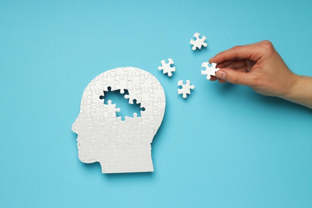 Puzzlekopf mit fehlenden Elementen auf blauem Hintergrund