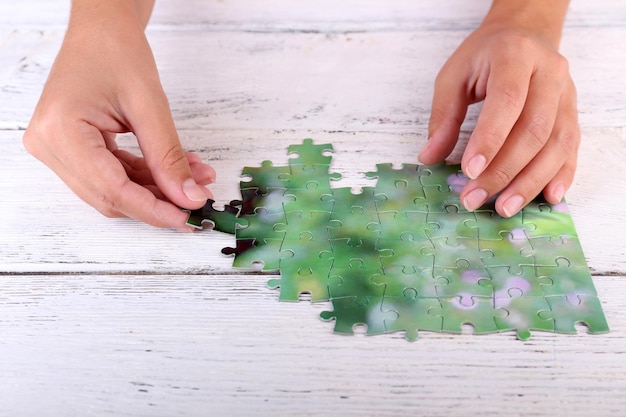 Foto puzzleteil in der hand auf hölzernem tischhintergrund