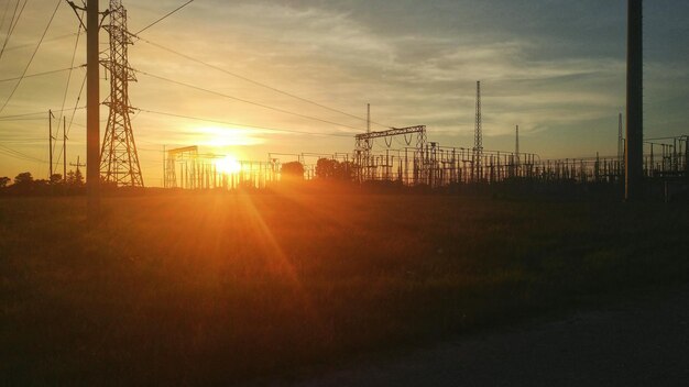 Foto pylones de electricidad en el campo contra el cielo durante la puesta de sol