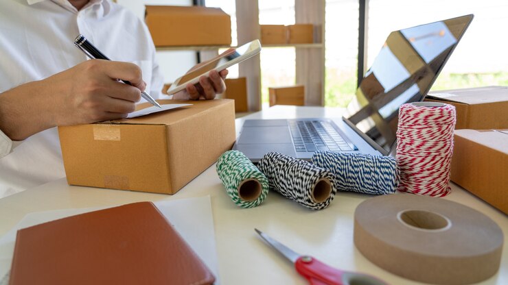 Foto pyme empresario de pequeñas empresas, joven asiático que trabaja con una computadora portátil y una caja de embalaje de entrega