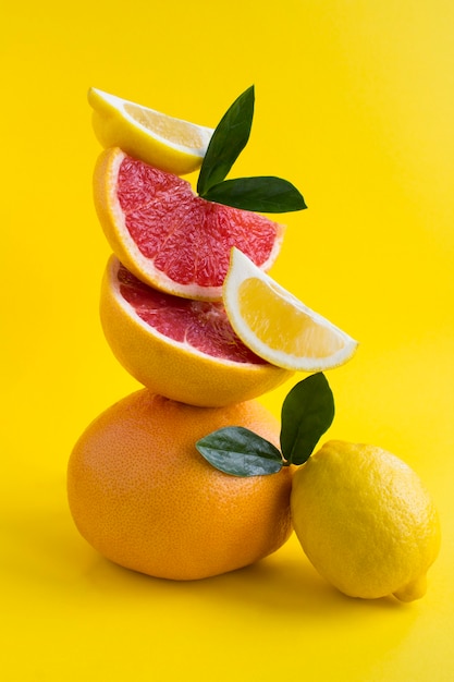 Pyramide aus Grapefruit und Zitrone im Gleichgewicht an der gelben Wand. Lage vertikal.