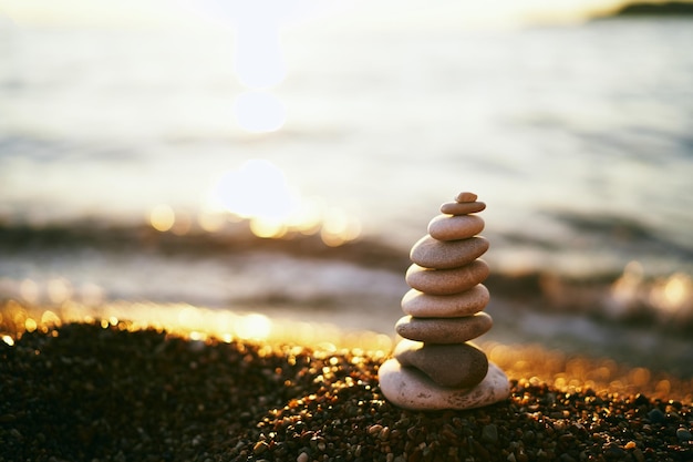 Pyramide aus Steinen liegt am Meer an den Strahlen der untergehenden Sonne