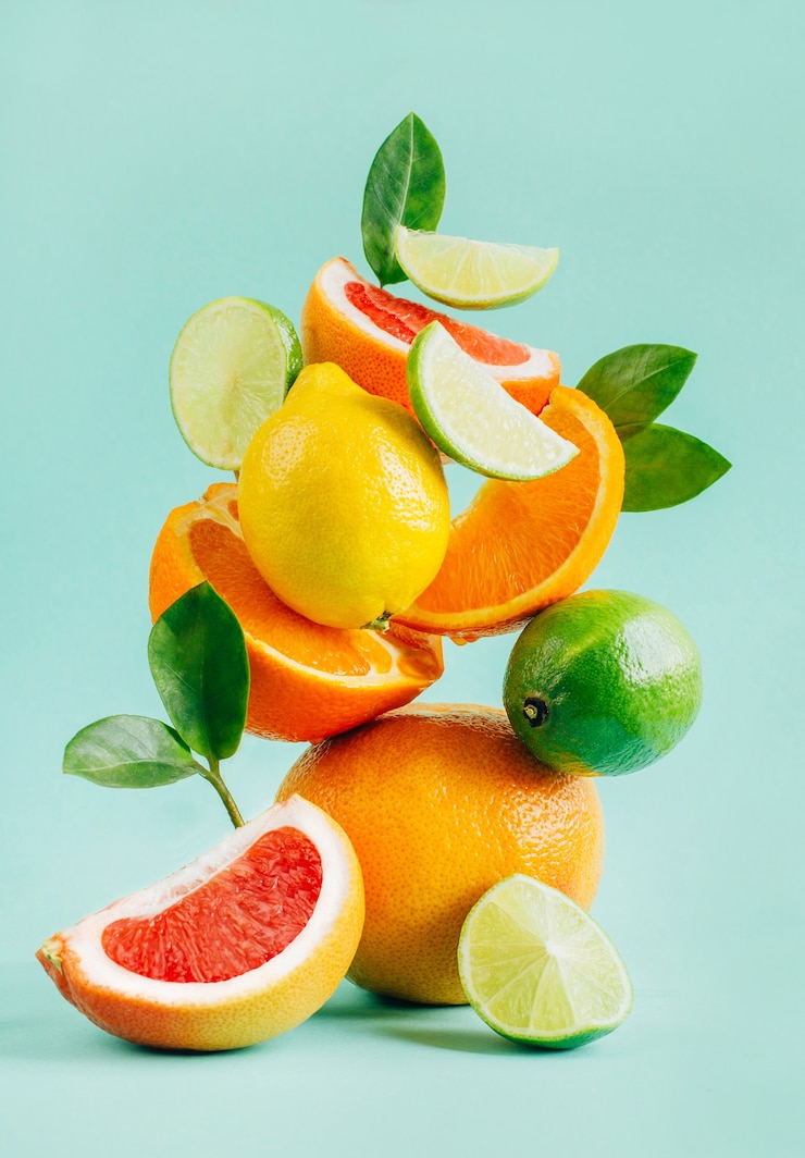 Foto pyramide aus zitrusgrapefruit, zitrone, orange und limette, verziert mit blättern auf blau