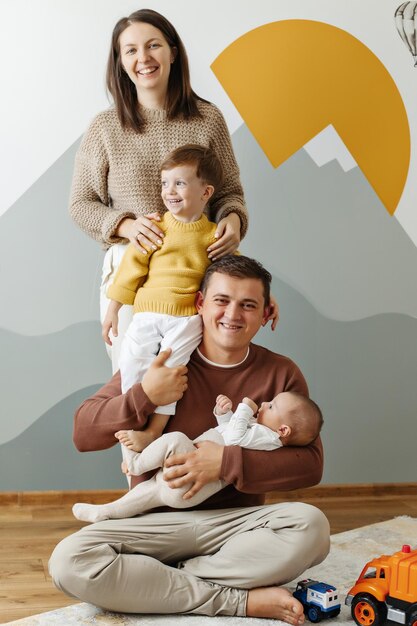 Pyramide der glücklichen Familie auf dem Hintergrund der Wand im Kinderzimmer Vater, Mutter und zwei Söhne