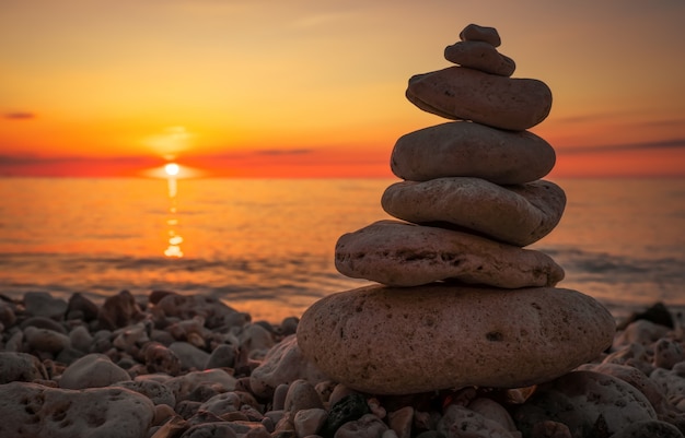 Pyramide der kleinen Kieselsteine am Strand. Steine, vor dem Hintergrund der Küste während des Sonnenuntergangs