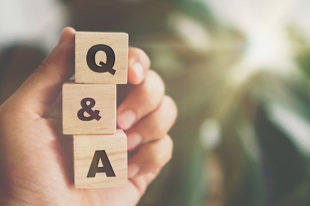 Q y A alfabeto en cubo de madera en mano. Concepto de significado de preguntas y respuestas.
