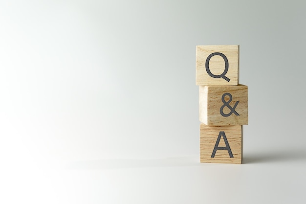 Q y un alfabeto en un cubo de madera en la mano con el fondo de pregunta y respuesta significado concepto