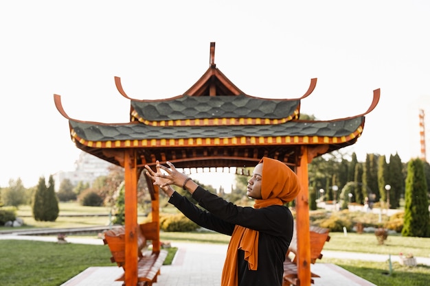 Qigong chinesische Meditation und Sporttraining im Freien. Schwarze muslimische Frau meditiert im Freien in der Nähe der chinesischen Laube.