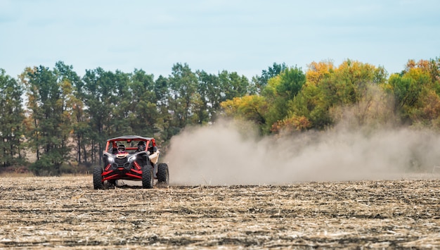 Quad in dichtem Staub fährt auf gepflügtem Feld