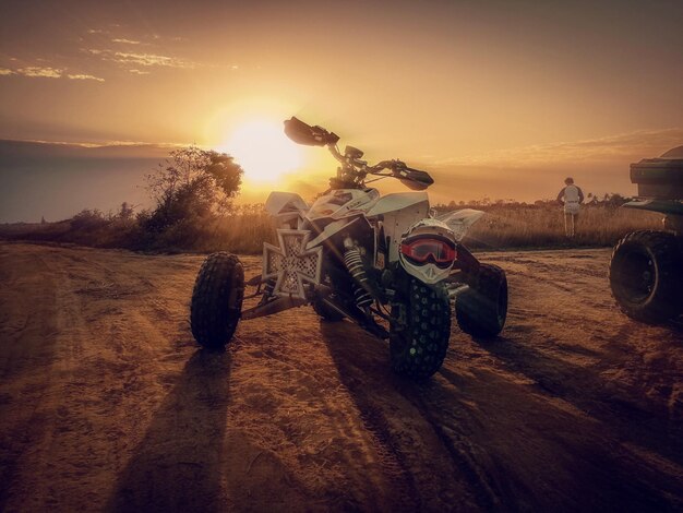 Quadbike en la arena contra el cielo durante la puesta de sol