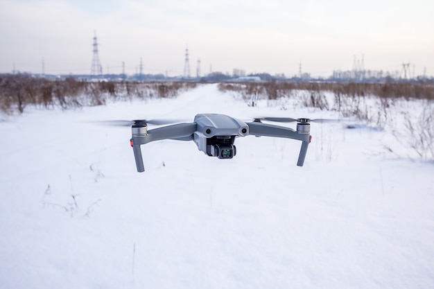 Quadcopter-Drohne, die im Winter über ein schneebedecktes Feld fliegt.