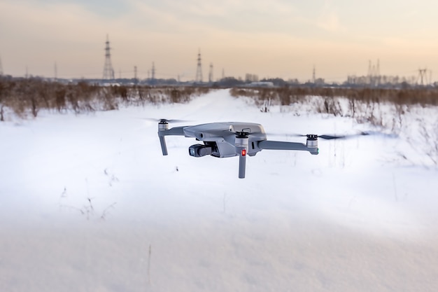 Quadcopter-Drohne fliegt im Winter über ein verschneites Feld
