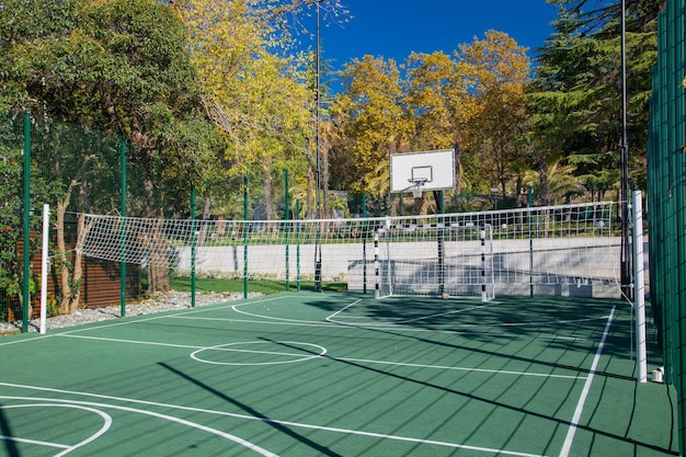Quadra de basquete ao ar livre com grama verde e céu azul ao fundo