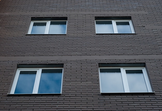 Quadratische Kunststofffenster an der Fassade eines Neubaus